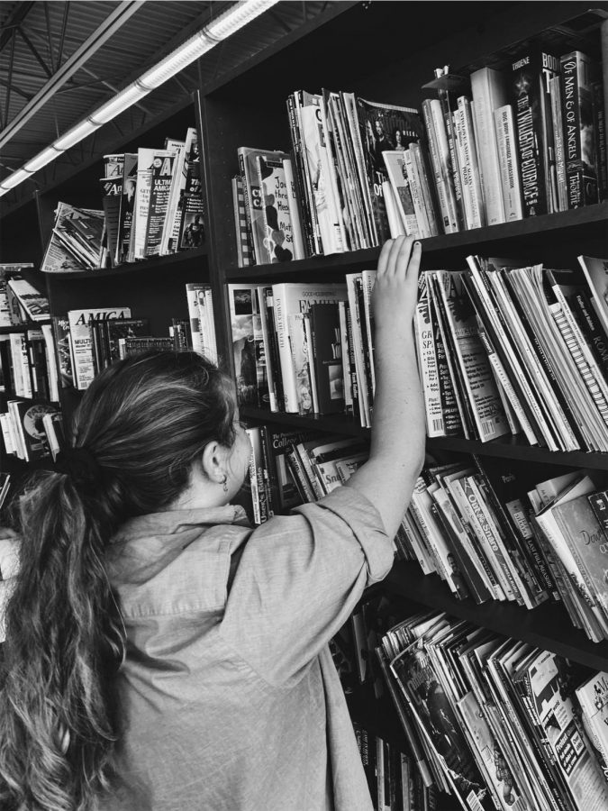 a picture of me in my dad's old shirt reaching for books at the top of the shelf